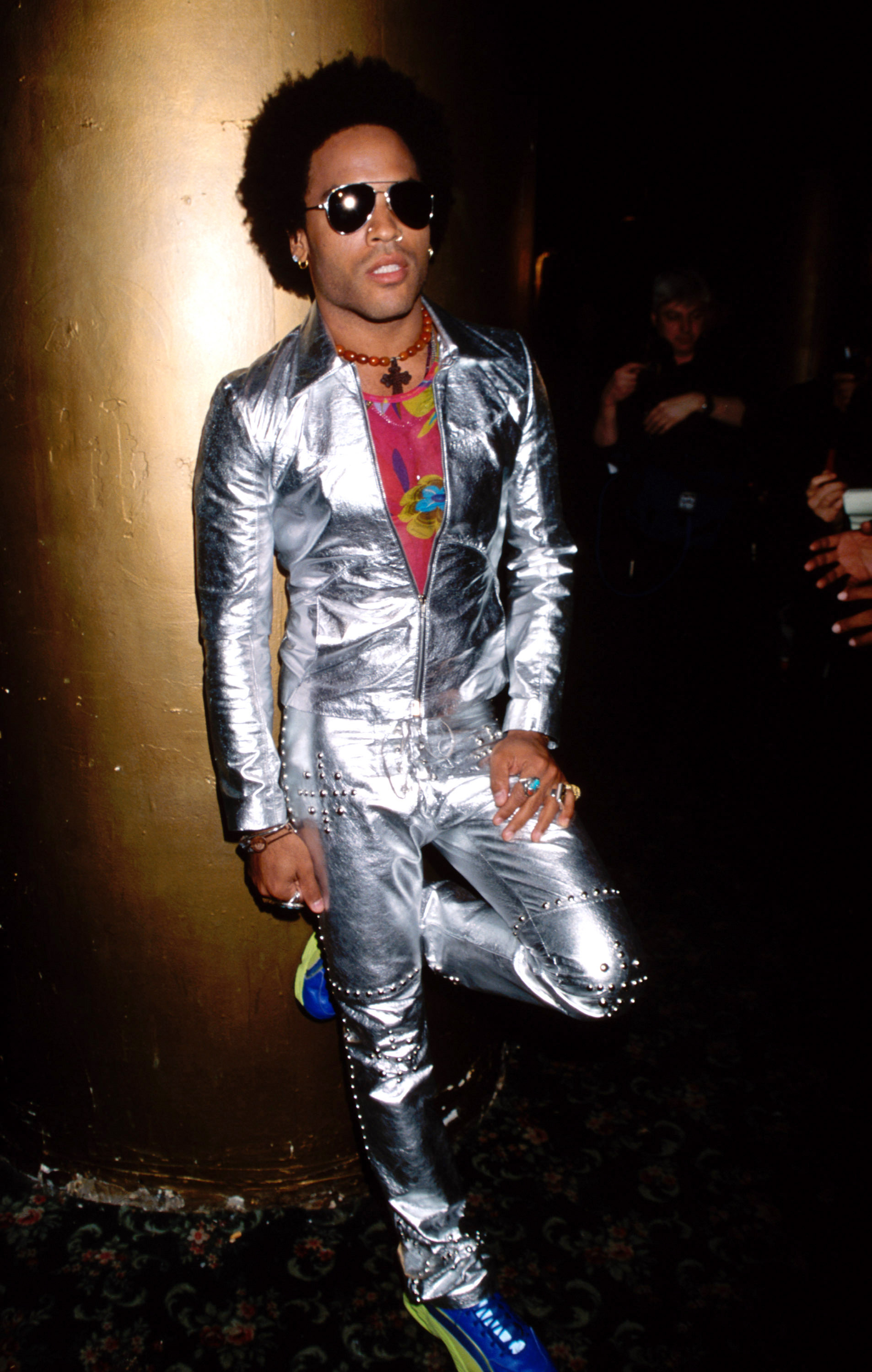 Person in a metallic suit with sneakers, accessorized with sunglasses and necklace