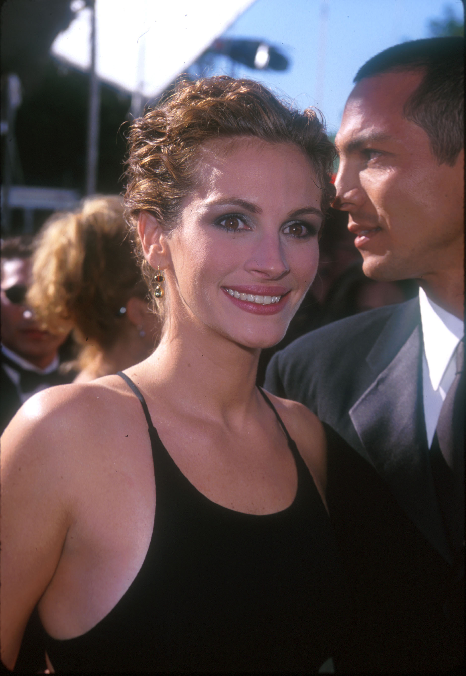 Julia Roberts in a black sleeveless dress posing next to an unidentifiable man on the red carpet