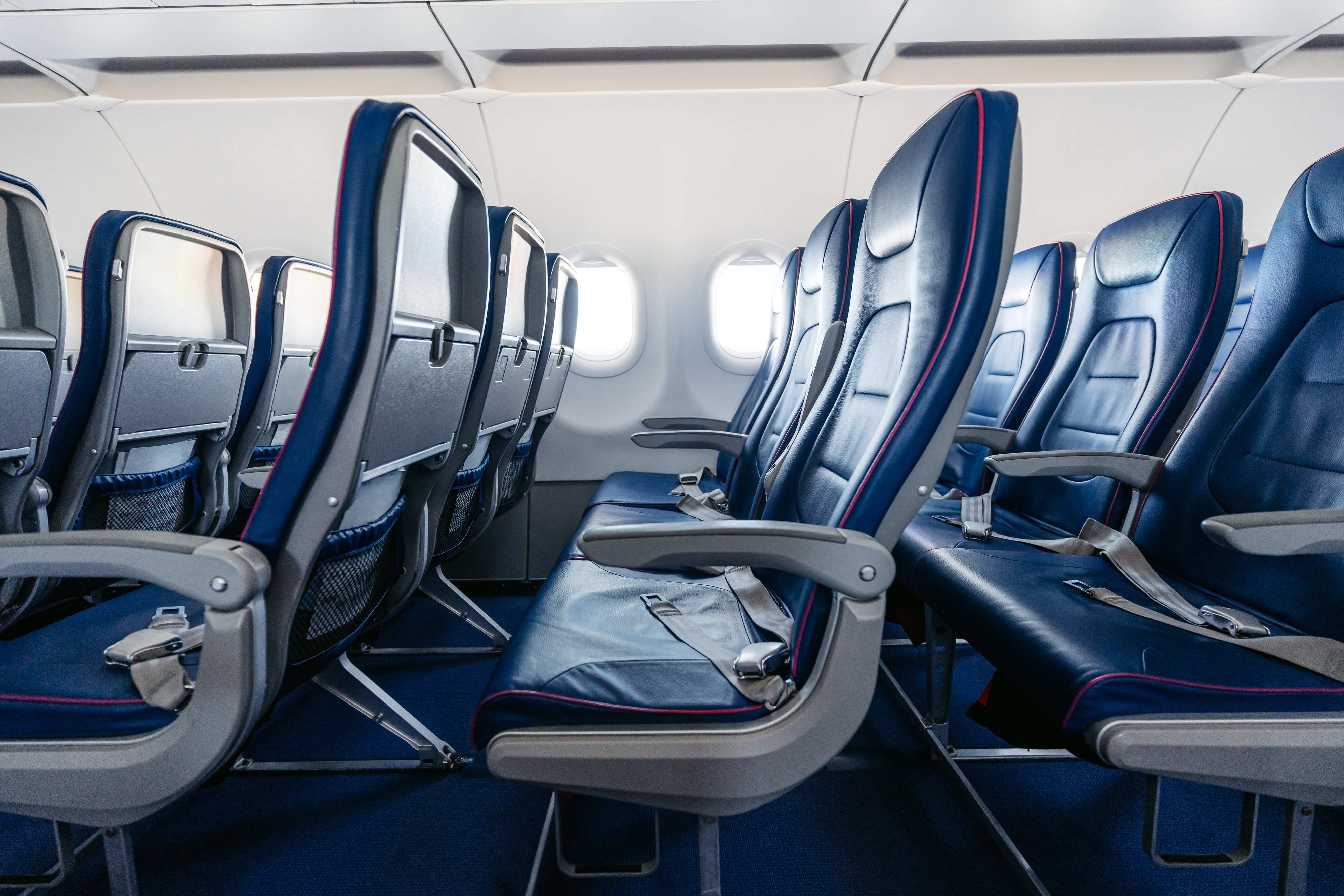 Rows of empty airplane seats with folded tray tables, highlighting travel comfort