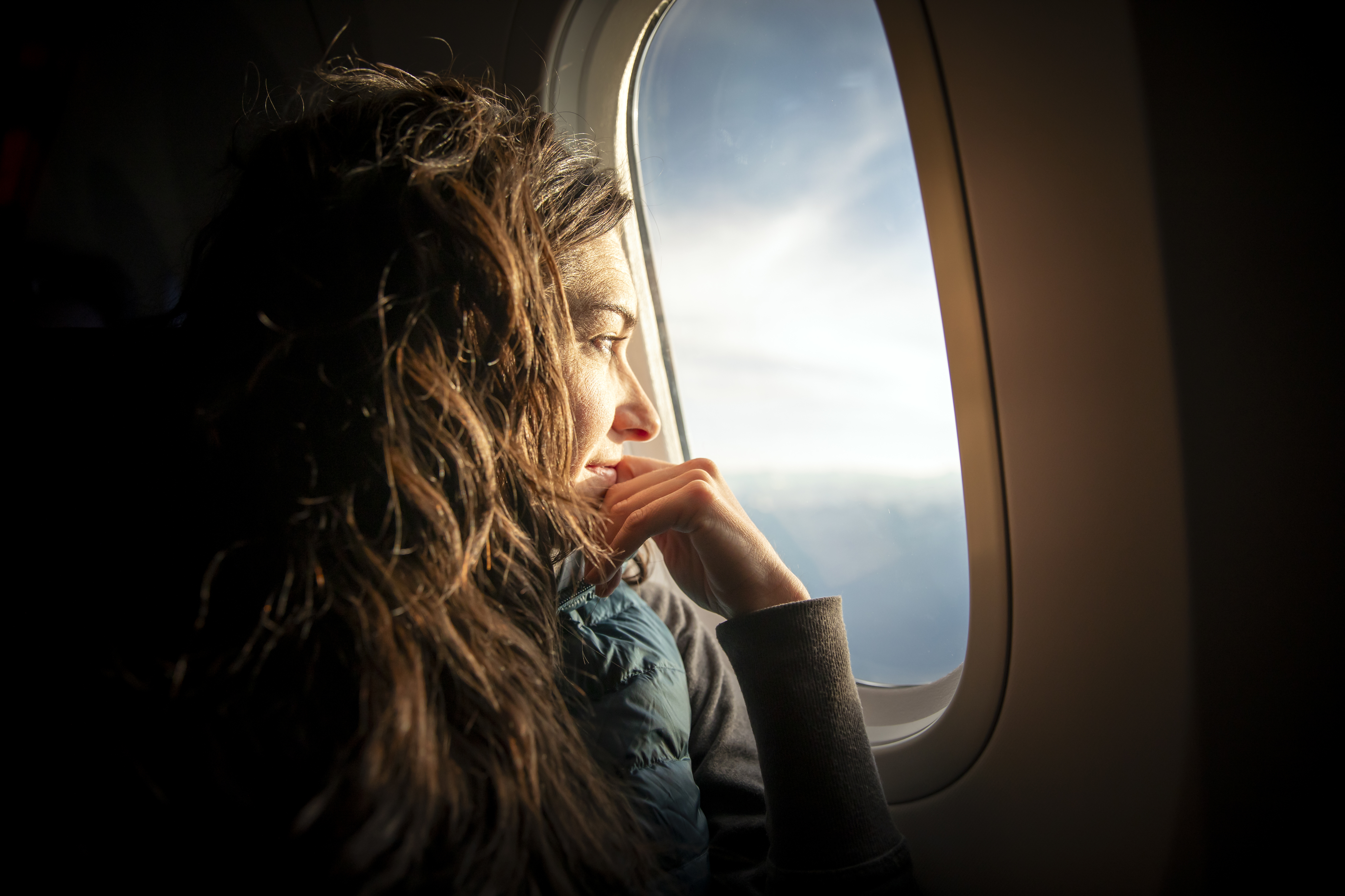 Woman looking out the window of an airplane, reflecting