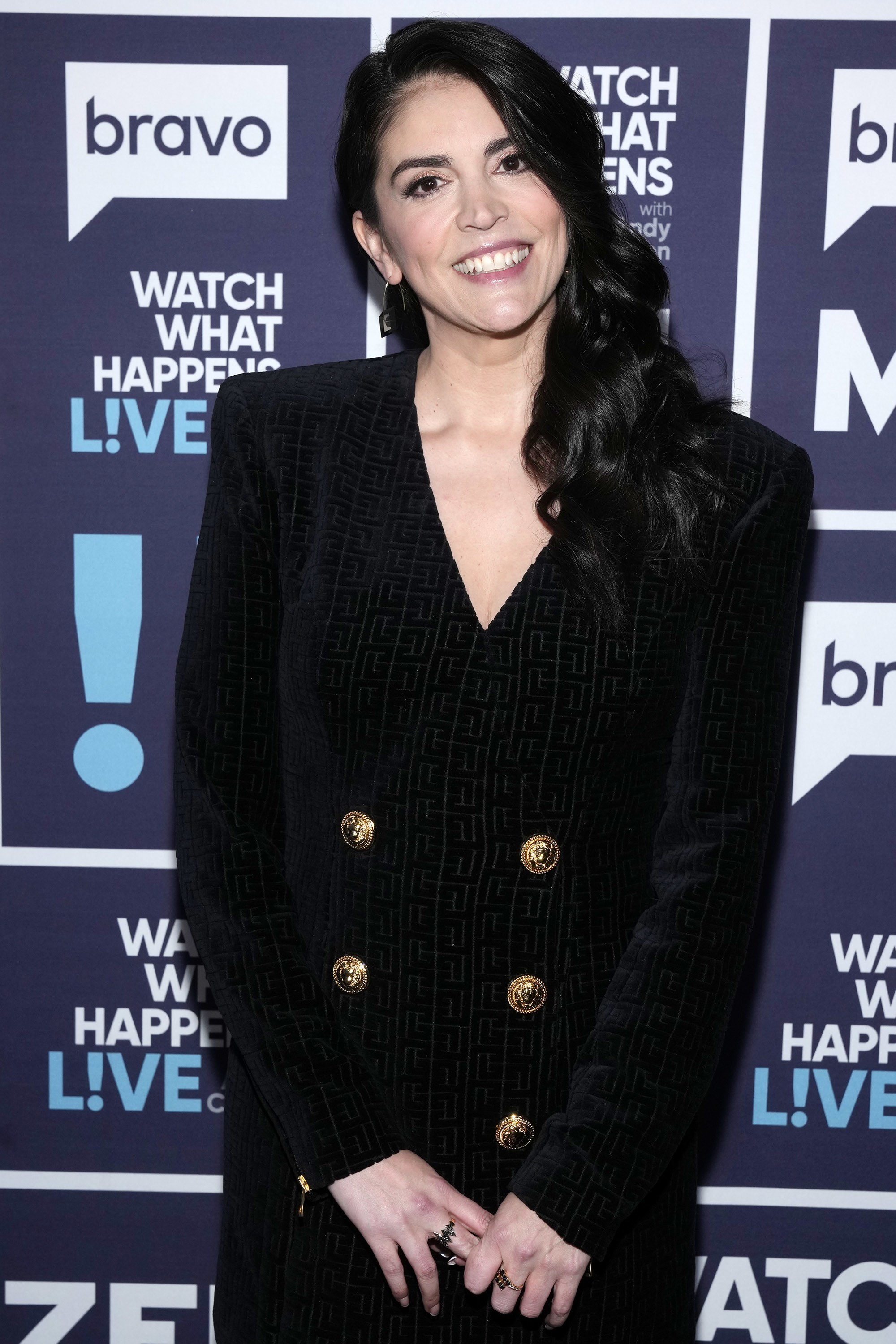 Smiling Cecily in black double-breasted blazer dress with gold buttons at a media event