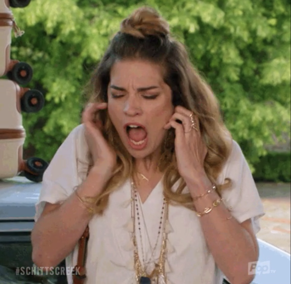 Alexis Rose from Schitt&#x27;s Creek appears stressed with hands on her ears
