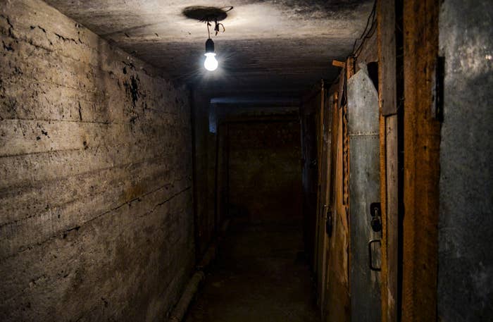 Dimly lit basement corridor with exposed pipes and a single lightbulb