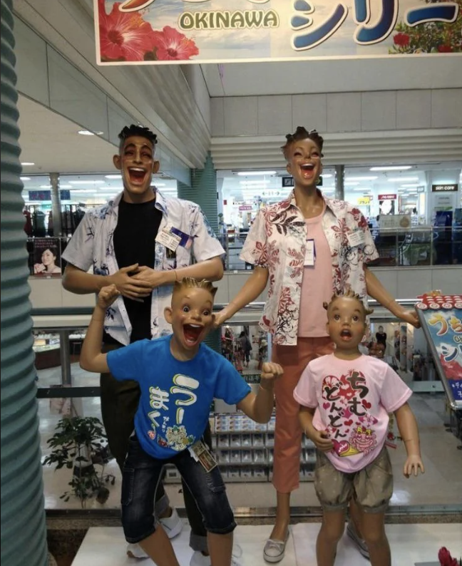 Four mannequins with exaggerated smiling faces wearing casual shirts and T-shirts, posing playfully in a store