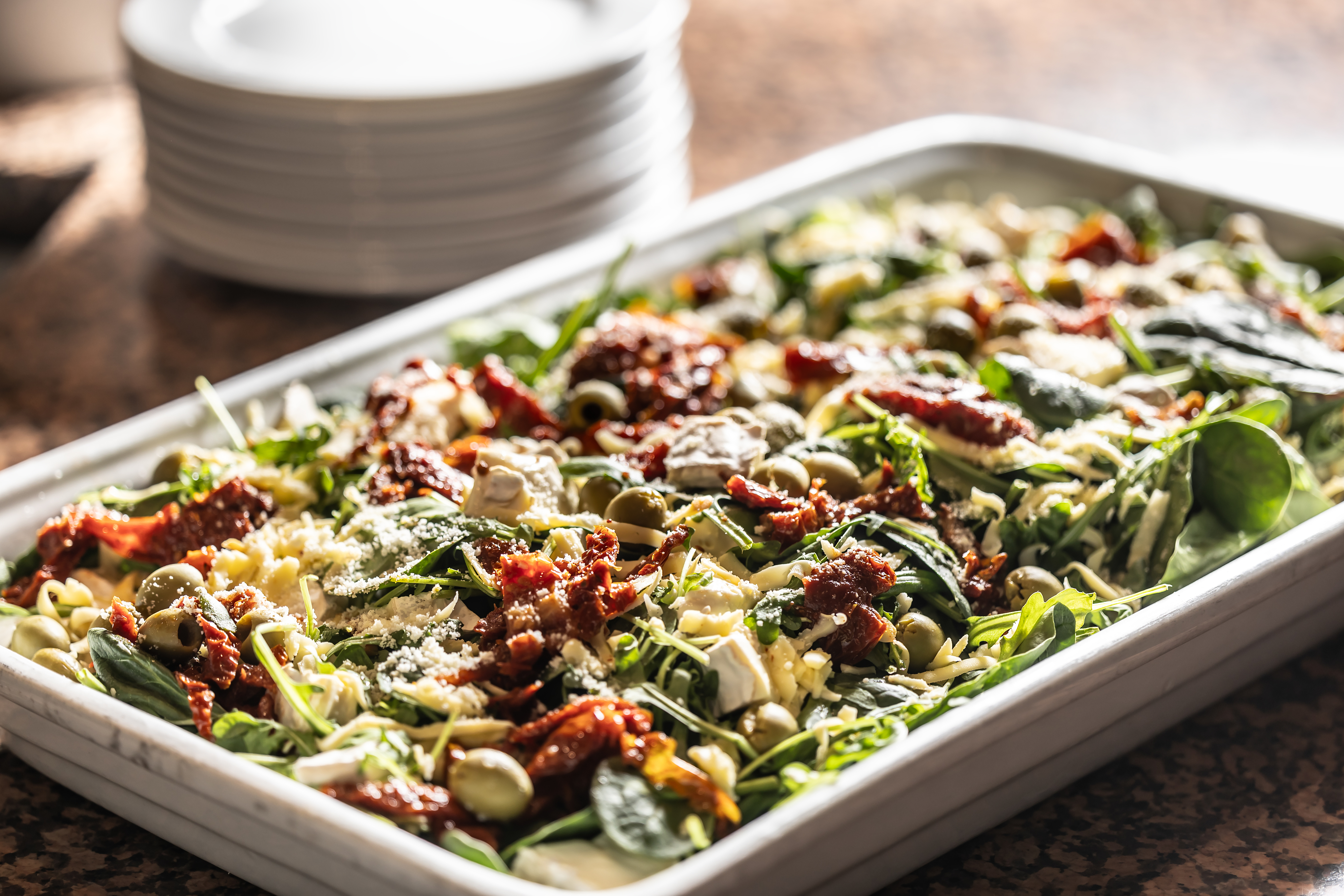 Tray with spinach salad, sundried tomatoes, seeds, grated cheese