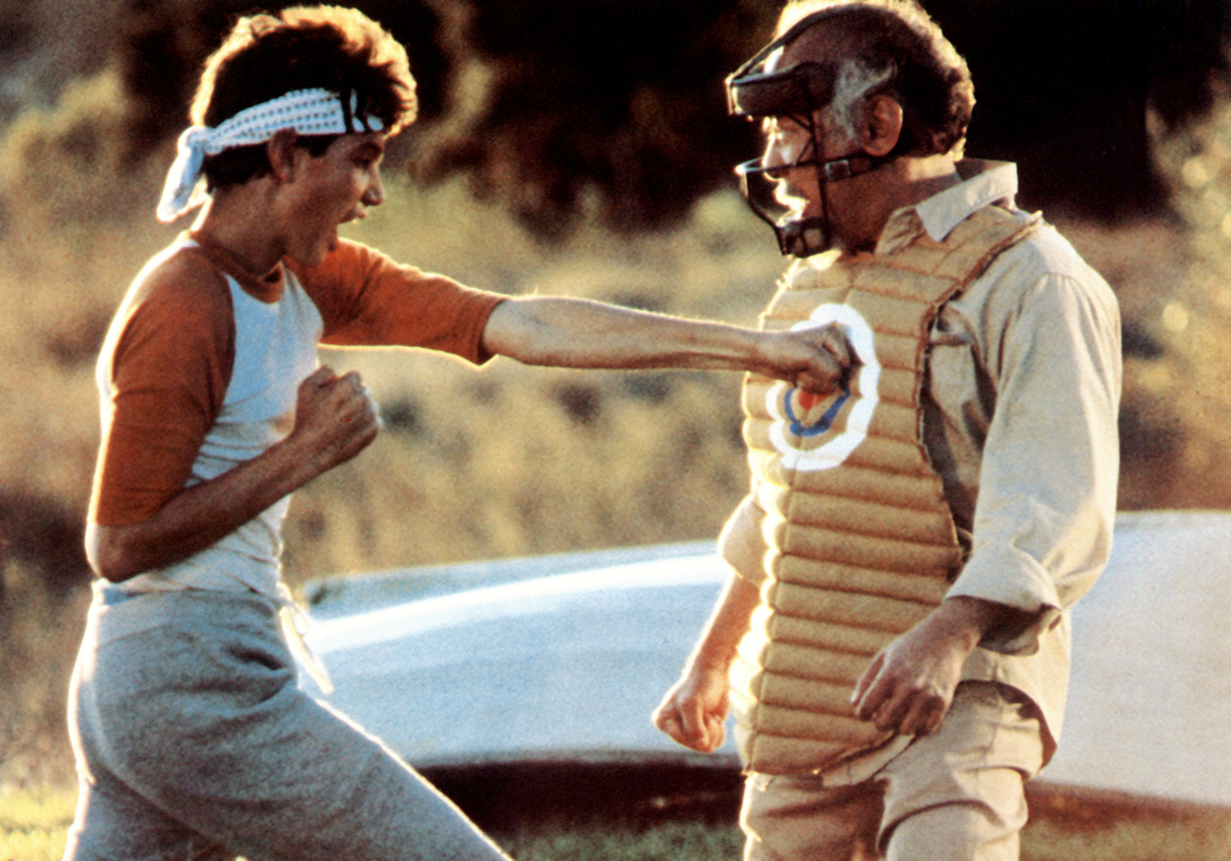 A scene from &#x27;The Karate Kid&#x27; with Daniel Larusso practicing a punch on Mr. Miyagi wearing protective body gear