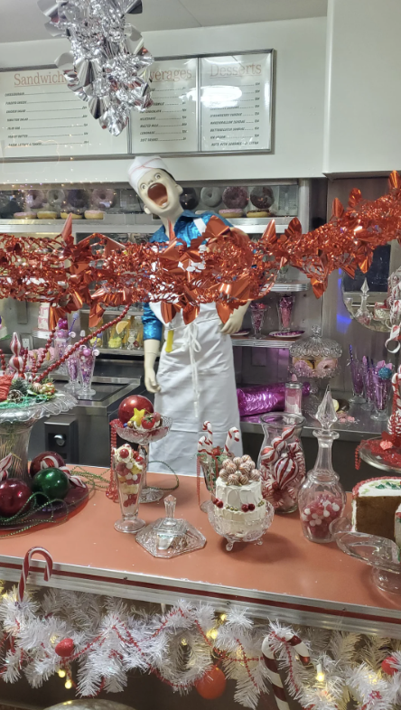Person in chef costume with open mouth expression standing behind a festive candy display