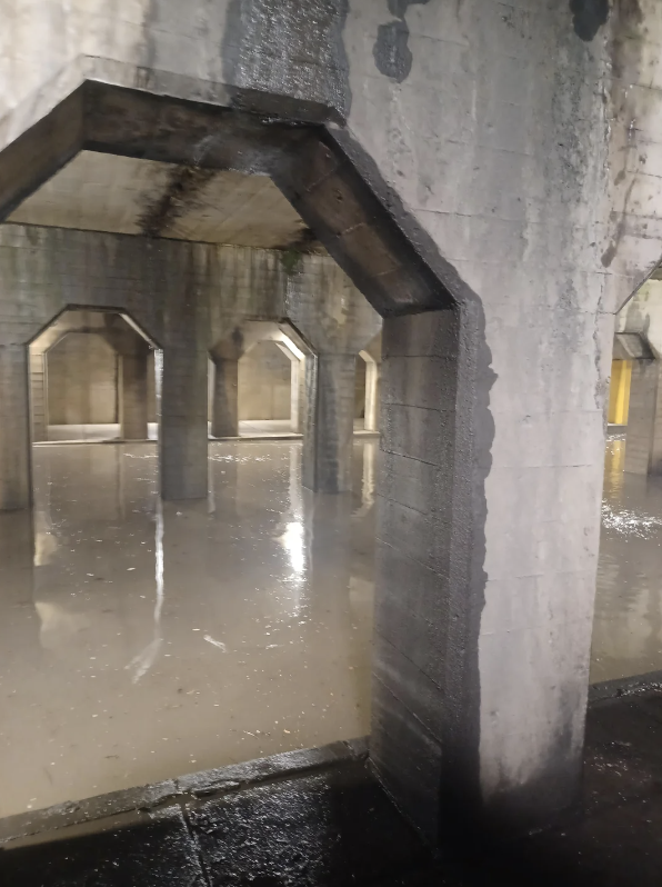 Concrete underground space with water on floor and multiple archways