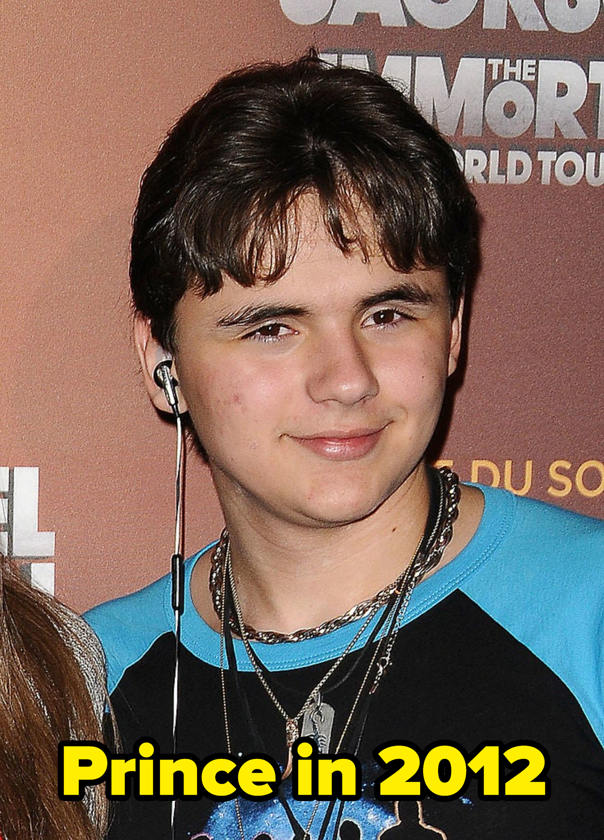 Young person with headphones around neck wearing a graphic t-shirt and a necklace