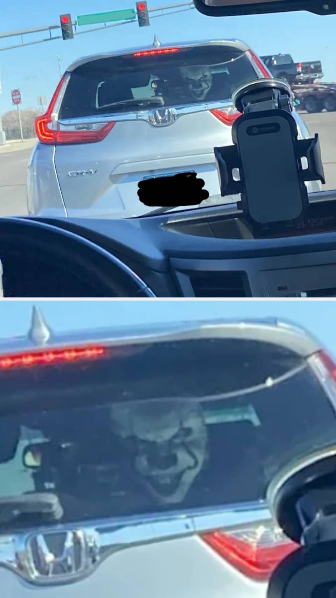 Image of a car&#x27;s rear with a reflection of a person&#x27;s face on the trunk, resembling a villainous grin