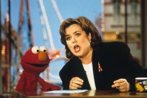 Elmo and Rosie O'Donnell at a talk show desk in a scene from a past television appearance