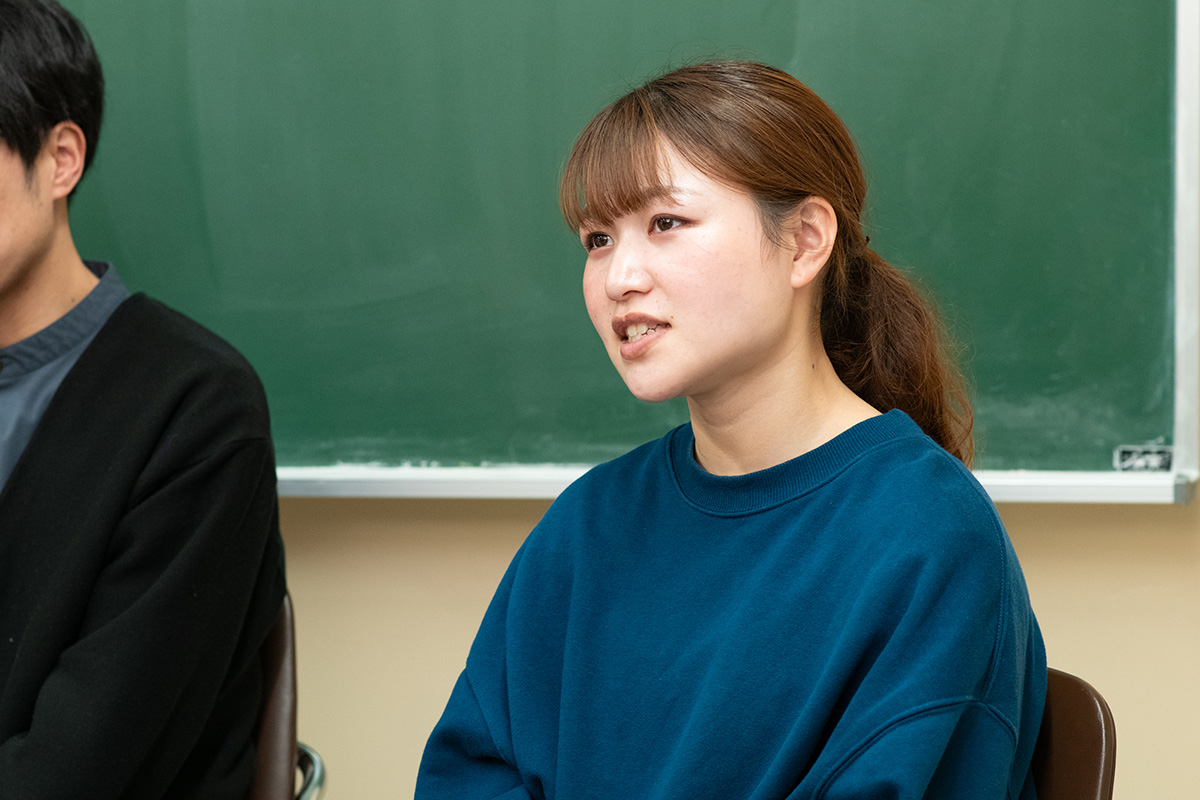 女性が話している様子、部屋の中で座っている。