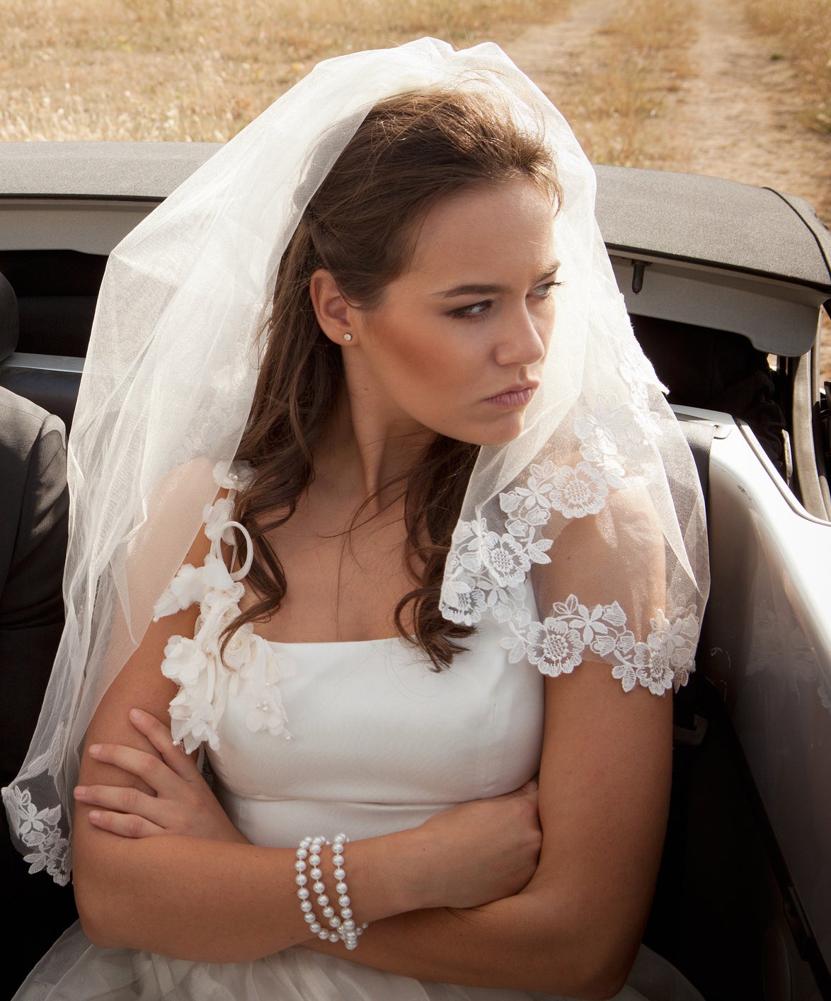 Bride and groom appear discontent in a car, groom on phone, bride looking away