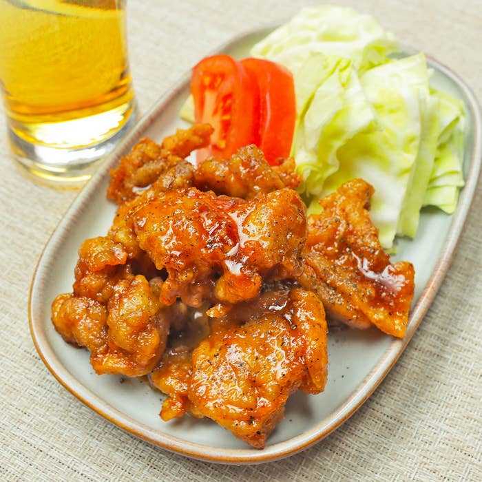 料理の皿にのった唐揚げとトマト、レタスがある。