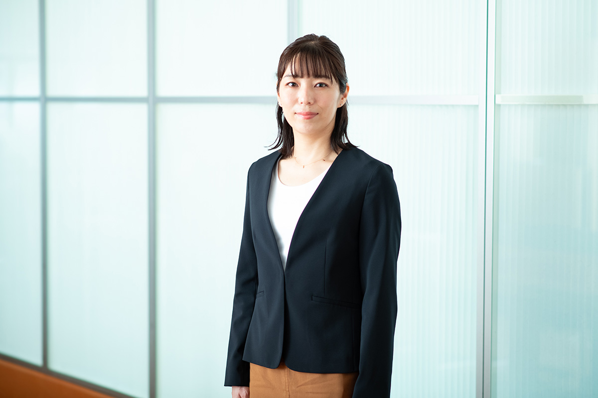 ビジネススーツを着た女性がオフィスでカメラに向かって立っている。