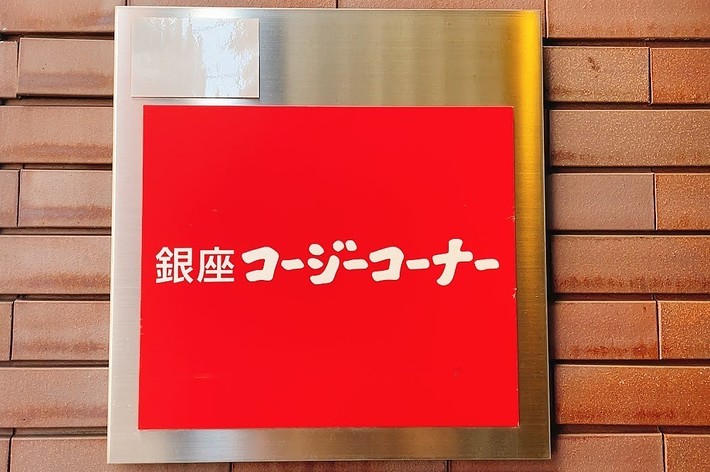 Sign in Japanese characters on a red background attached to a brick wall