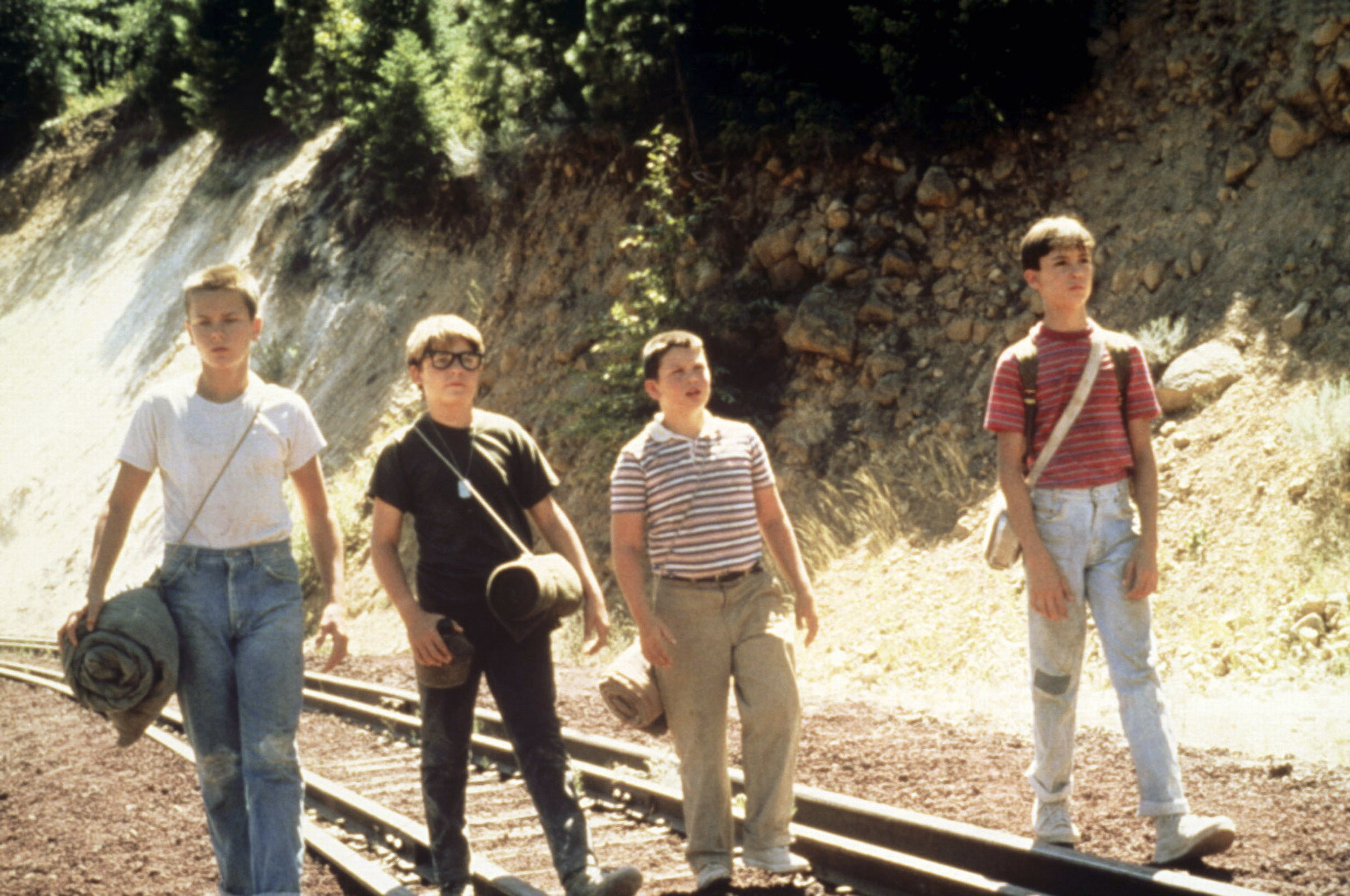 Four boys from the film &quot;Stand by Me&quot; walking on railroad tracks in casual attire