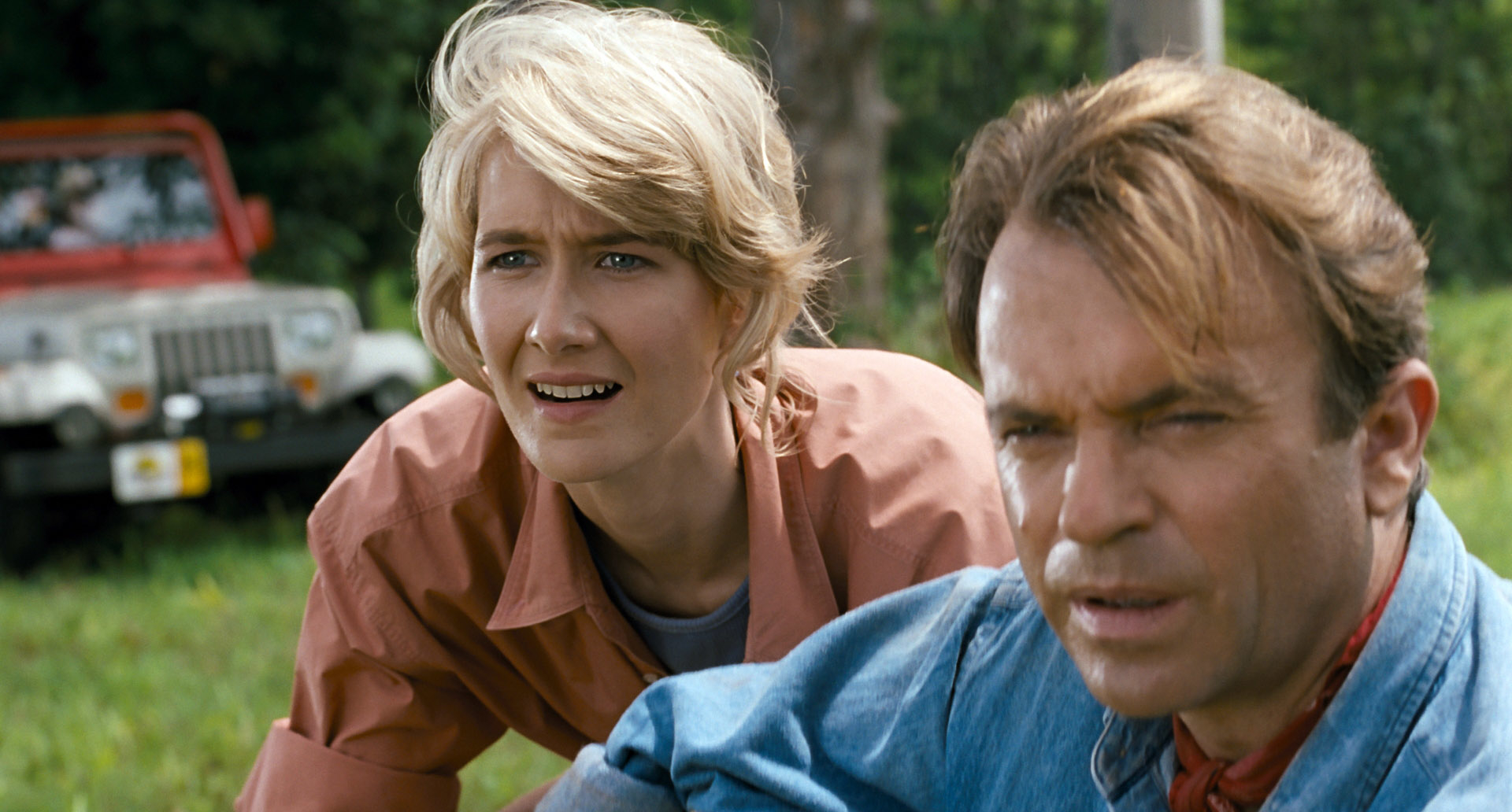 Two characters from Jurassic Park, Ellie Sattler and Alan Grant, show concern as they look off-screen