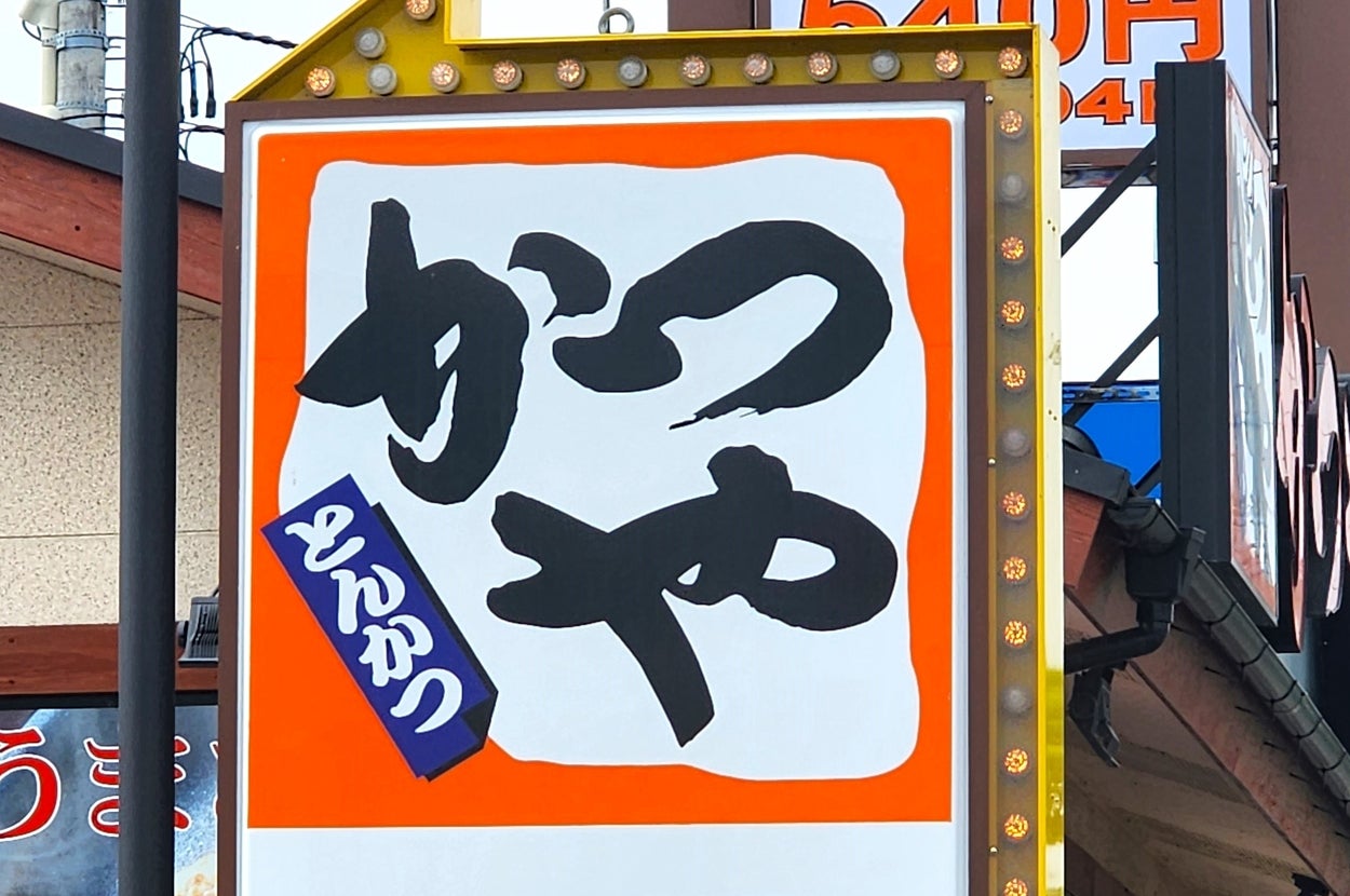 看板には大きな文字で「めん」と書かれ、下には駐車場を指す矢印があります。