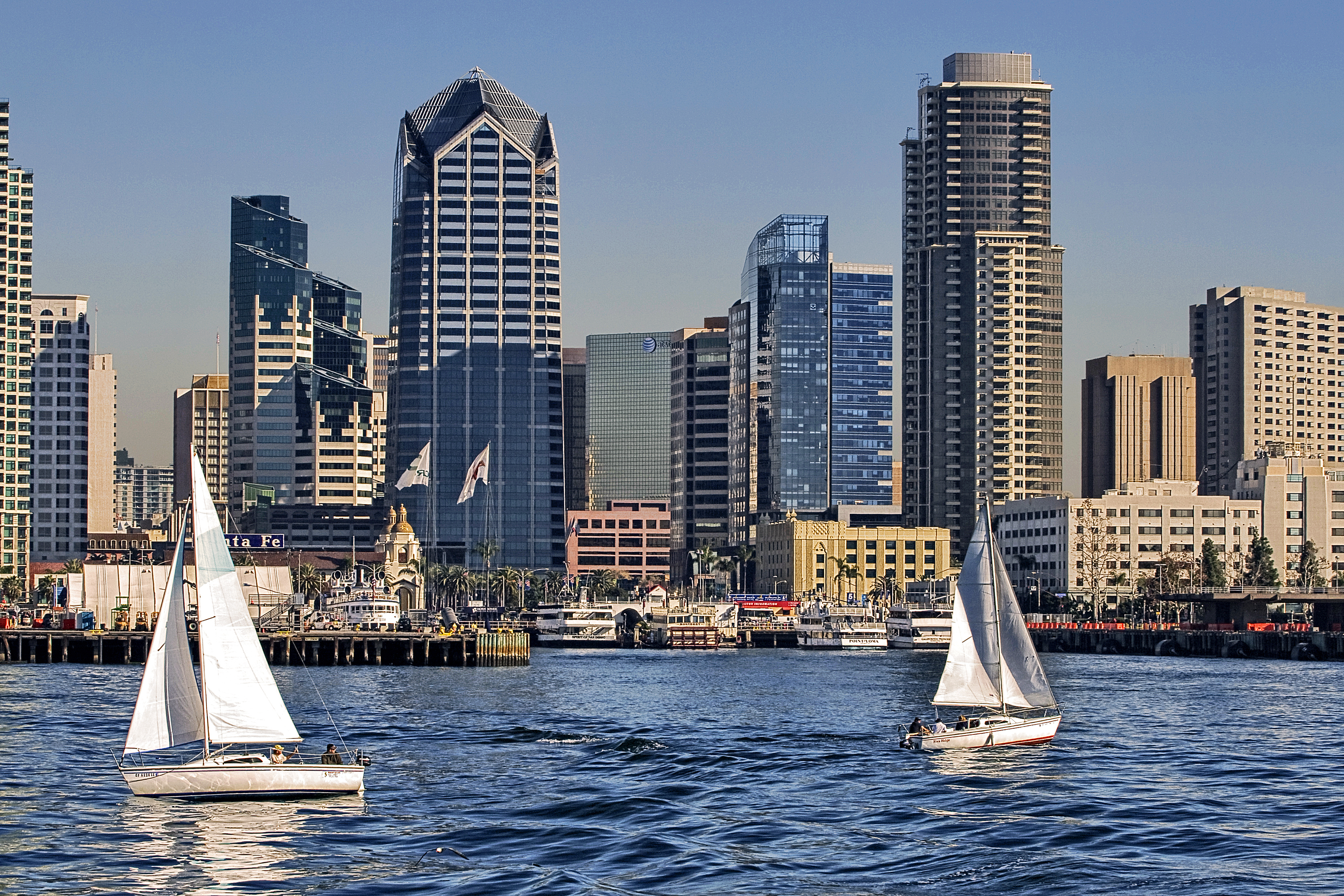 Sailboats in a harbor with a backdrop of a city skyline, depicting a travel destination