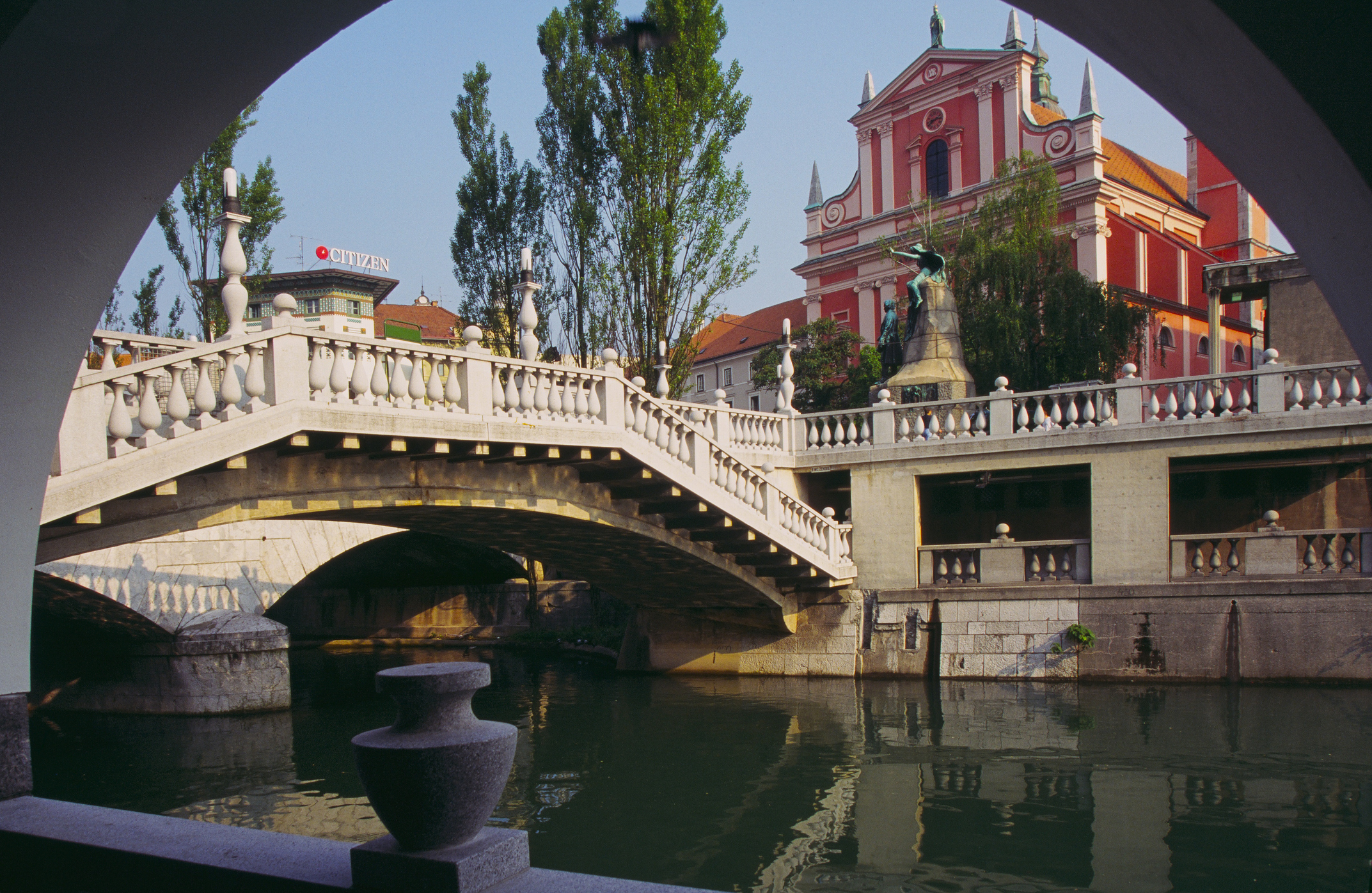 View of a historic bridge and church from under an archway, in a scenic European city