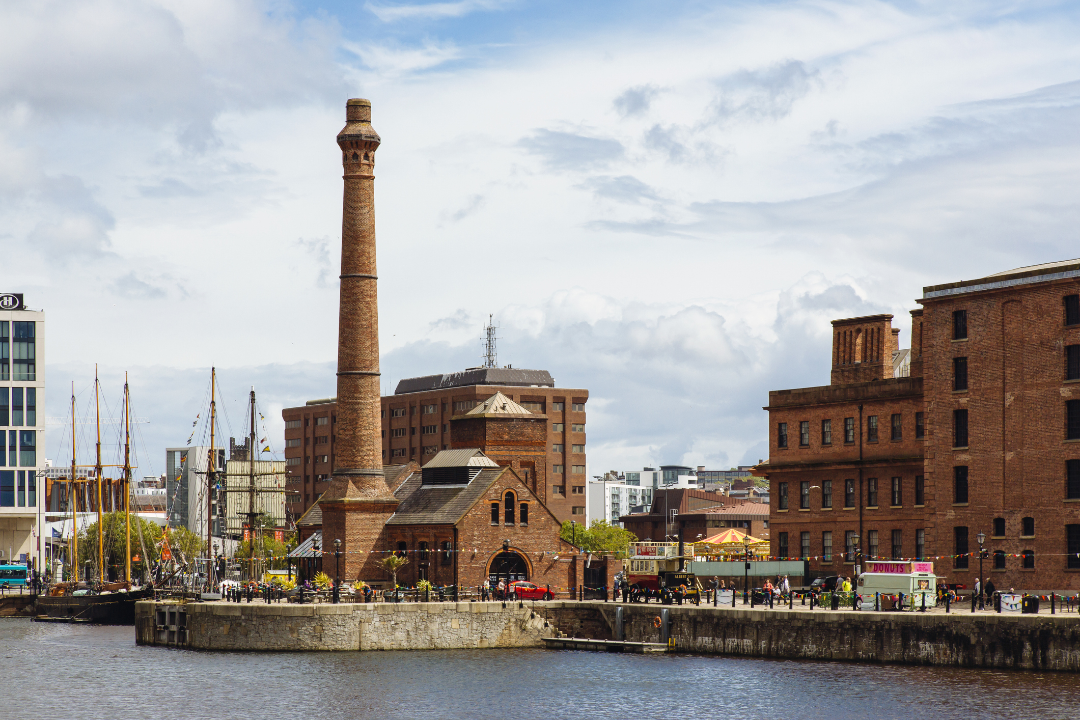 Historic waterfront buildings with a prominent chimney tower near a dock with boats