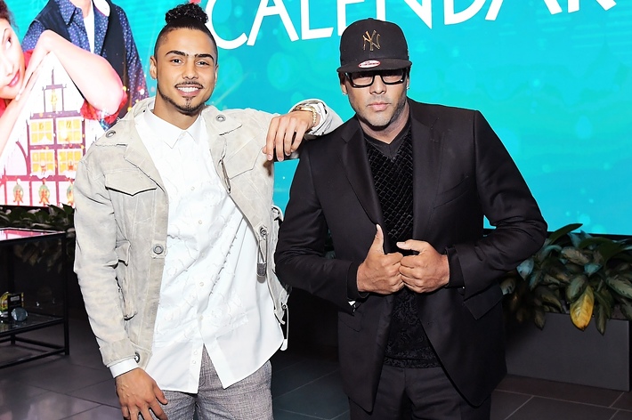 Two men posing for a photo at an event, one in a light jacket and the other in a black suit