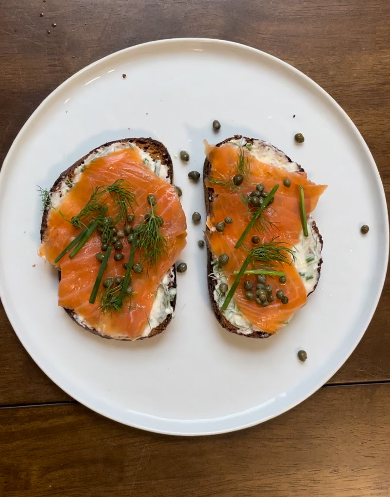 Plate with two slices of toast topped with cream cheese, smoked salmon, and herbs