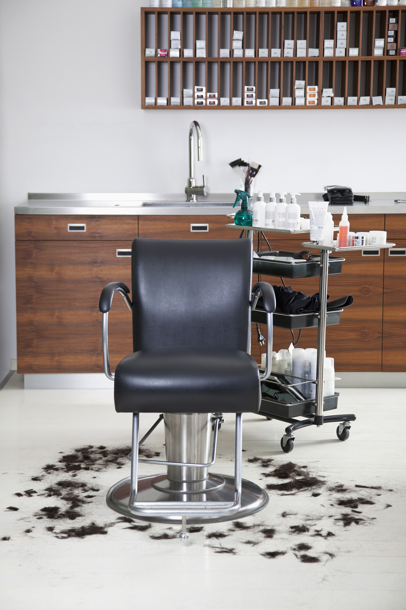 Barber chair in a salon with hair trimmings on the floor, signifying a recent haircut