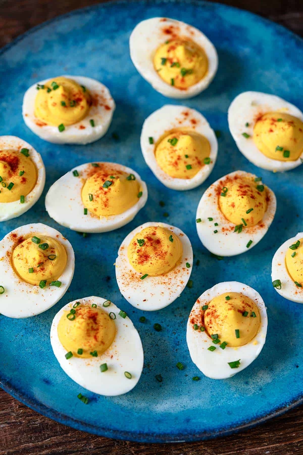A plate of deviled eggs garnished with paprika and chives