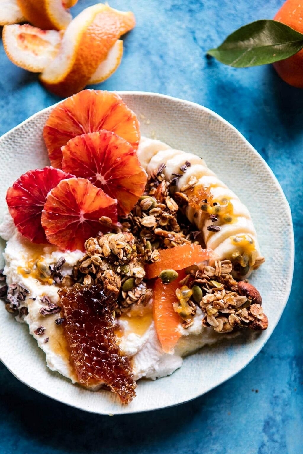 A plate with yogurt, granola, honeycomb, and slices of banana and citrus fruits
