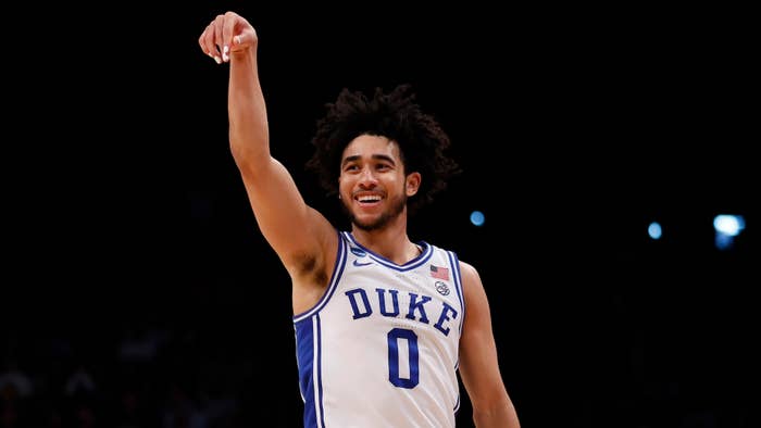 Basketball player in Duke uniform pointing upwards on the court