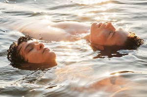 Simon and Wilhelm from "Young Royals" laying side by side in a lake together.