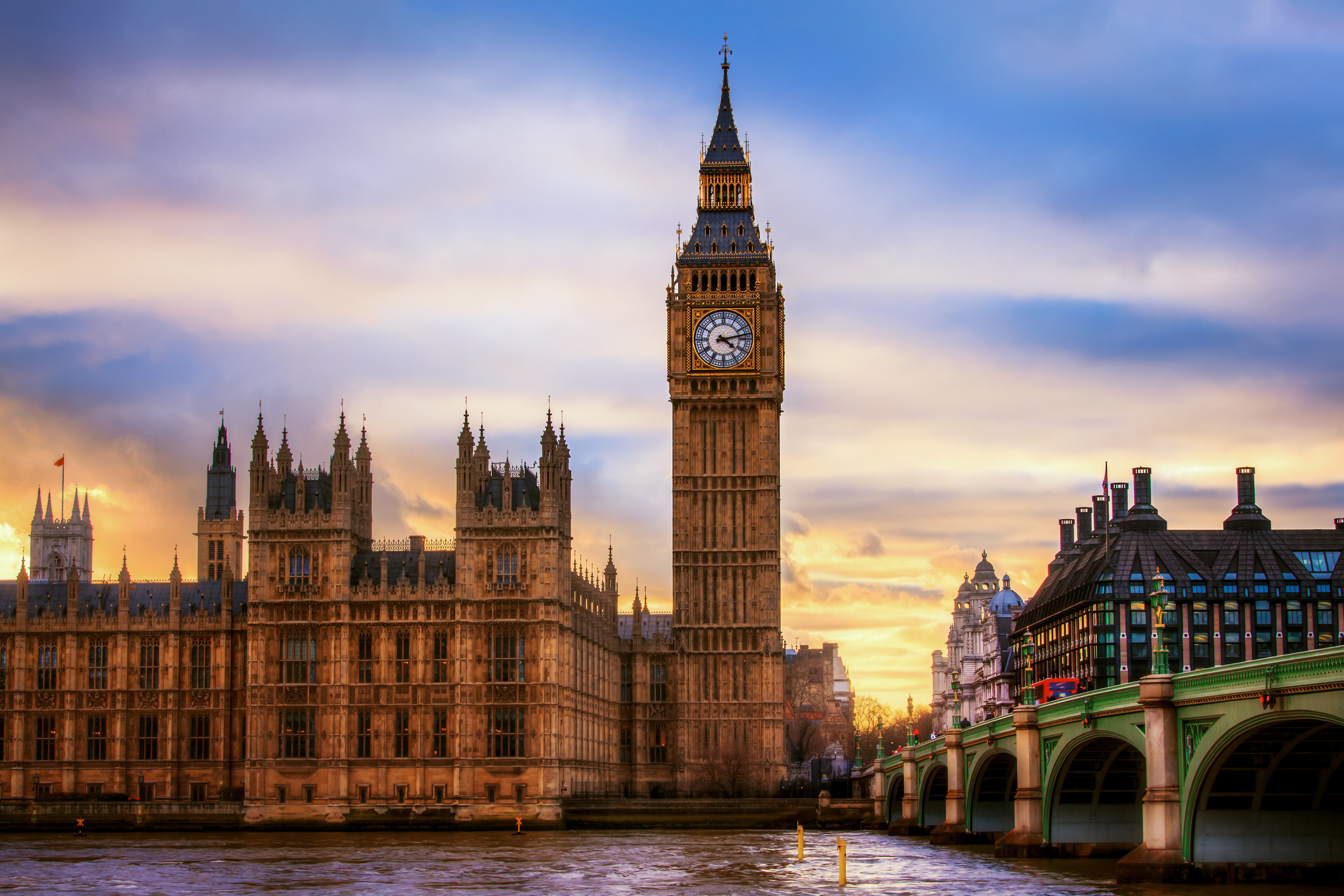 Big Ben and the Houses of Parliament next to a river at sunset