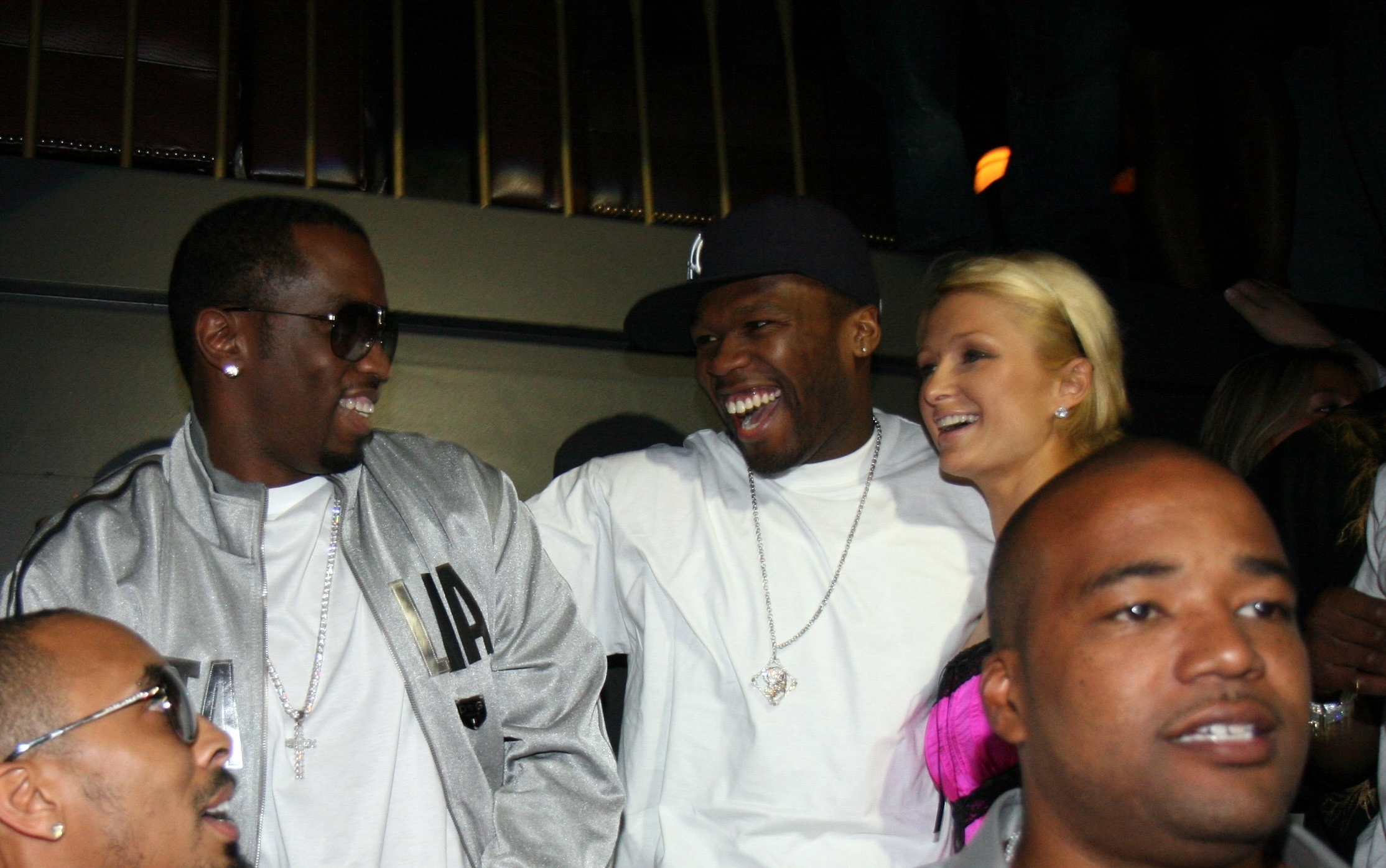 Sean Combs and 50 Cent in matching gray outfits share a laugh with Paris Hilton, who wears a light top