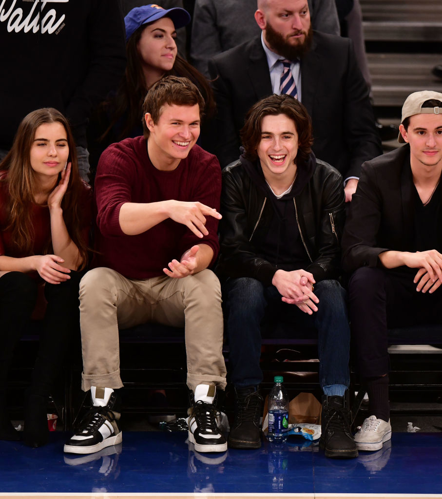 Four friends seated courtside laughing and enjoying a basketball game