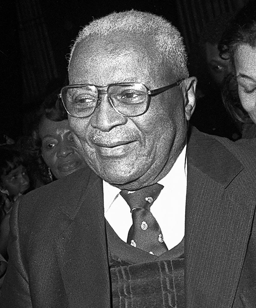 Smiling elderly man in glasses and suit with a patterned tie