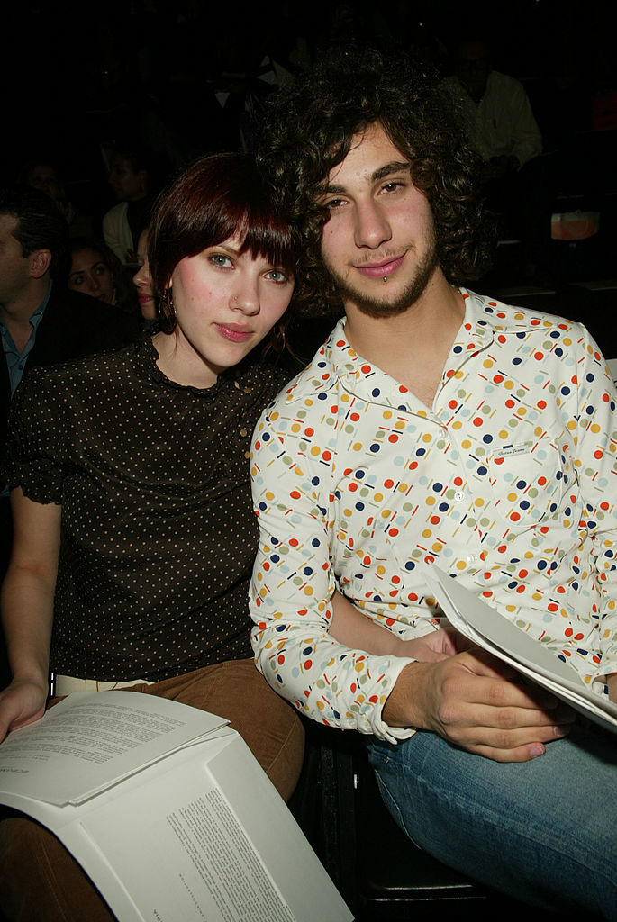 Two individuals sitting together, one in a polka-dot shirt, the other in a patterned top