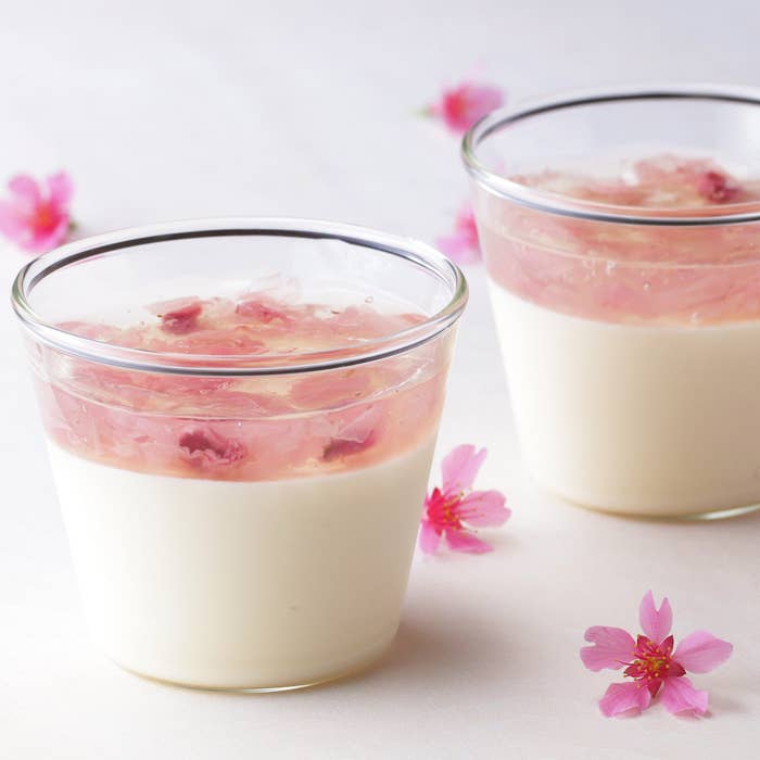 桜の花が添えられた2つのレアチーズケーキのカップ