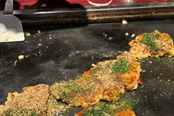 焼き台の上で調理された半分食べられたお好み焼き。