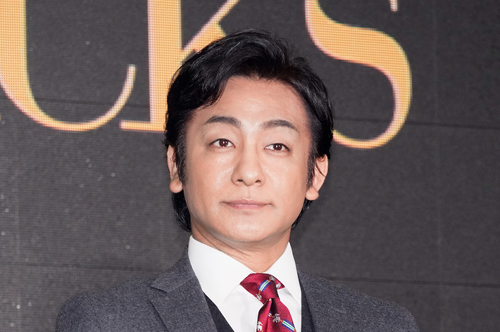 着物姿の男性がトロフィーを持っています。