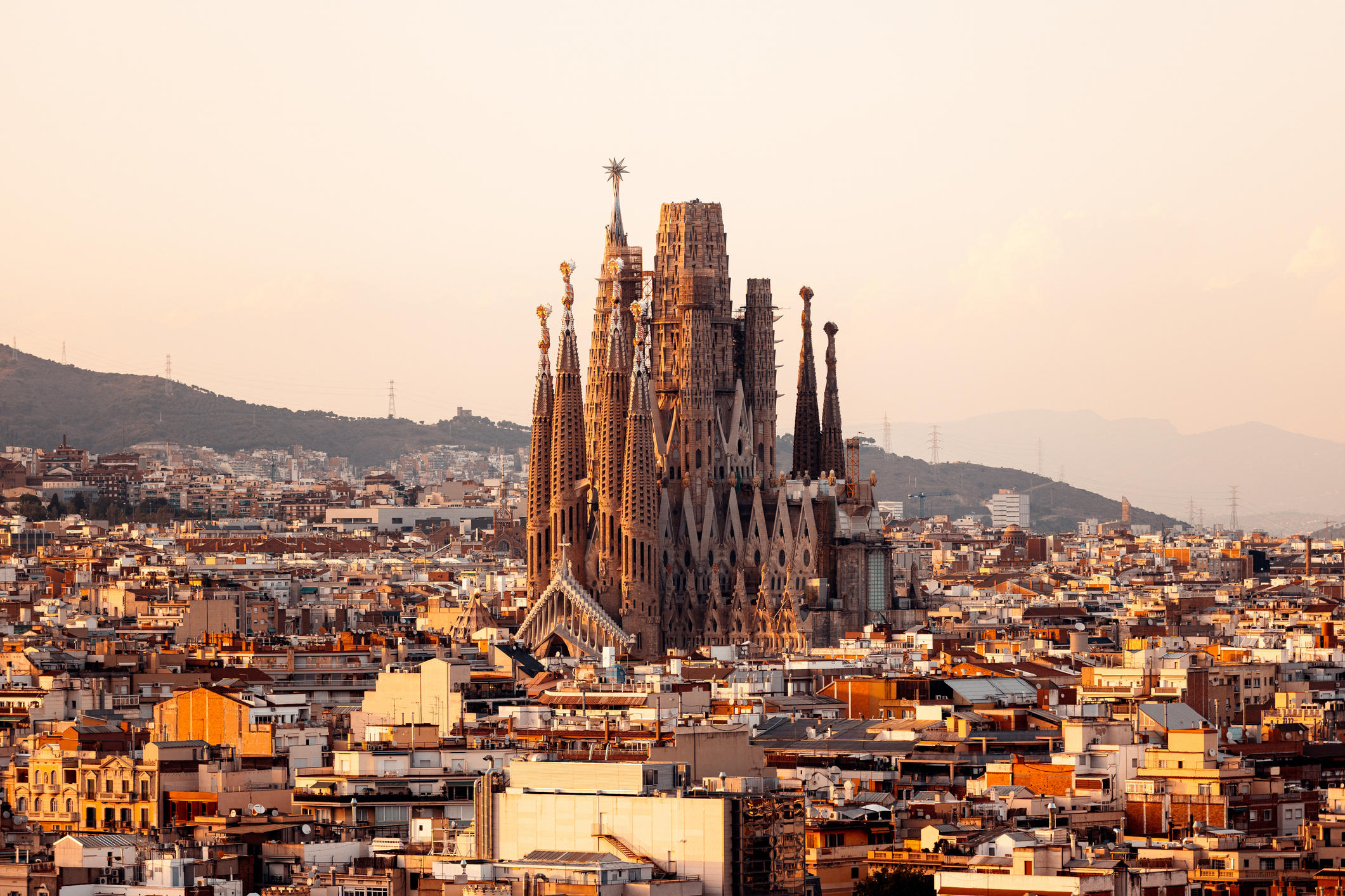 Sagrada Familia cathedral towers over Barcelona&#x27;s cityscape at sunset