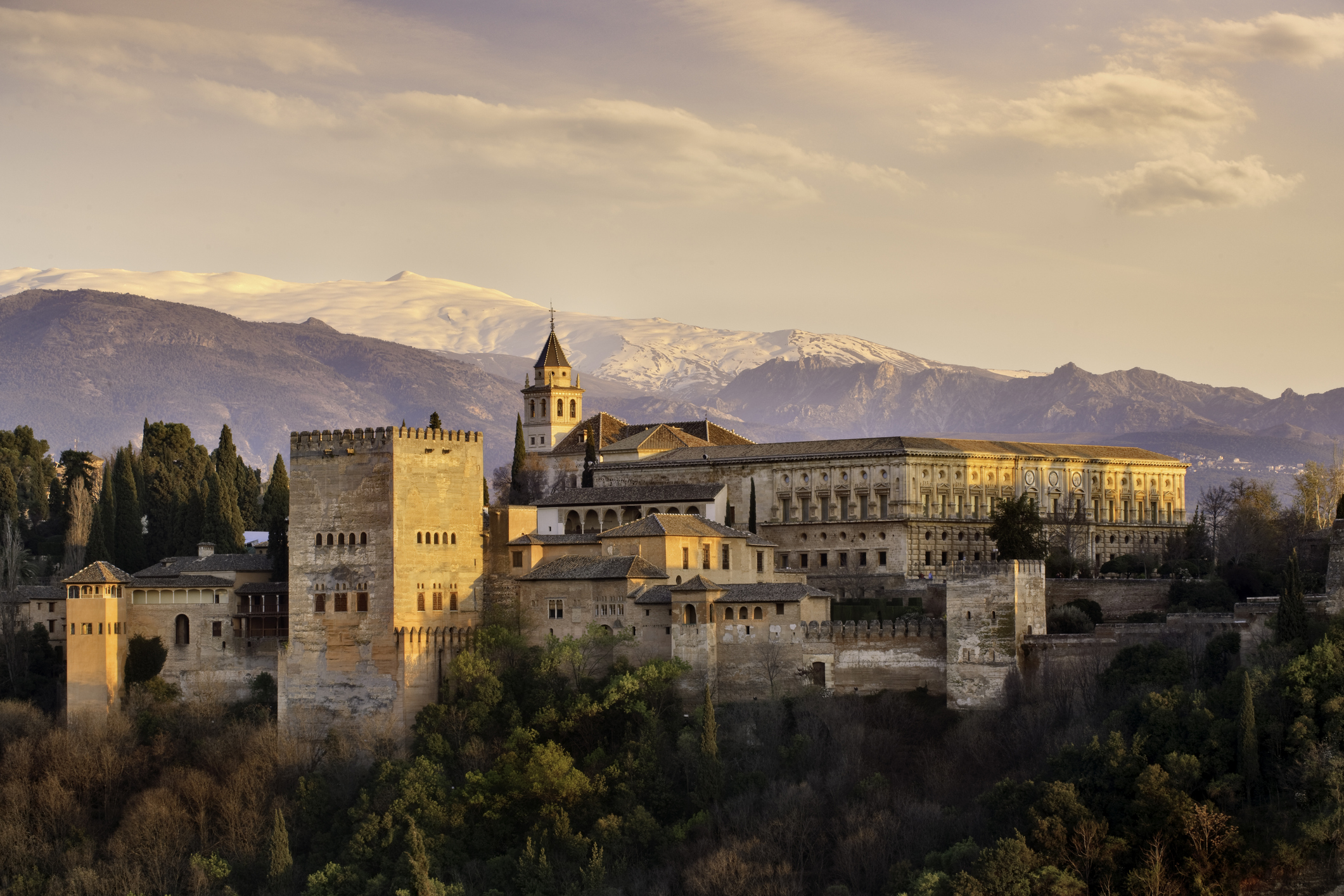 Historic Alhambra palace with background mountains at sunset