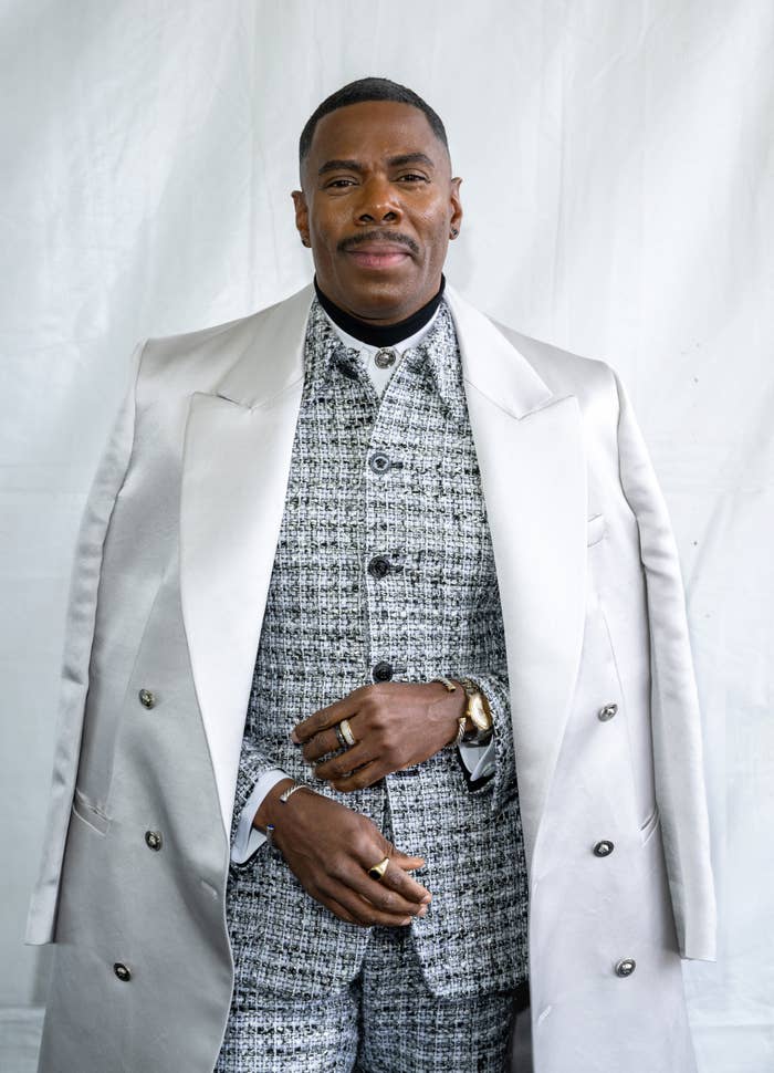 Colman Domingo in a patterned suit with overcoat posing for the camera
