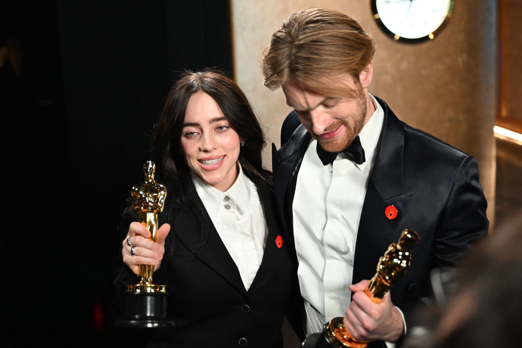 Billie and Finneas smiling holding their Oscar trophies