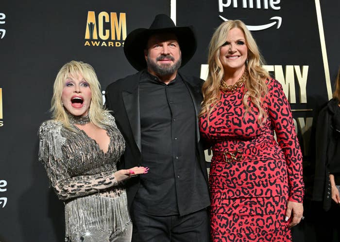 Three musicians posing, two women and one man, in formal attire at an award show