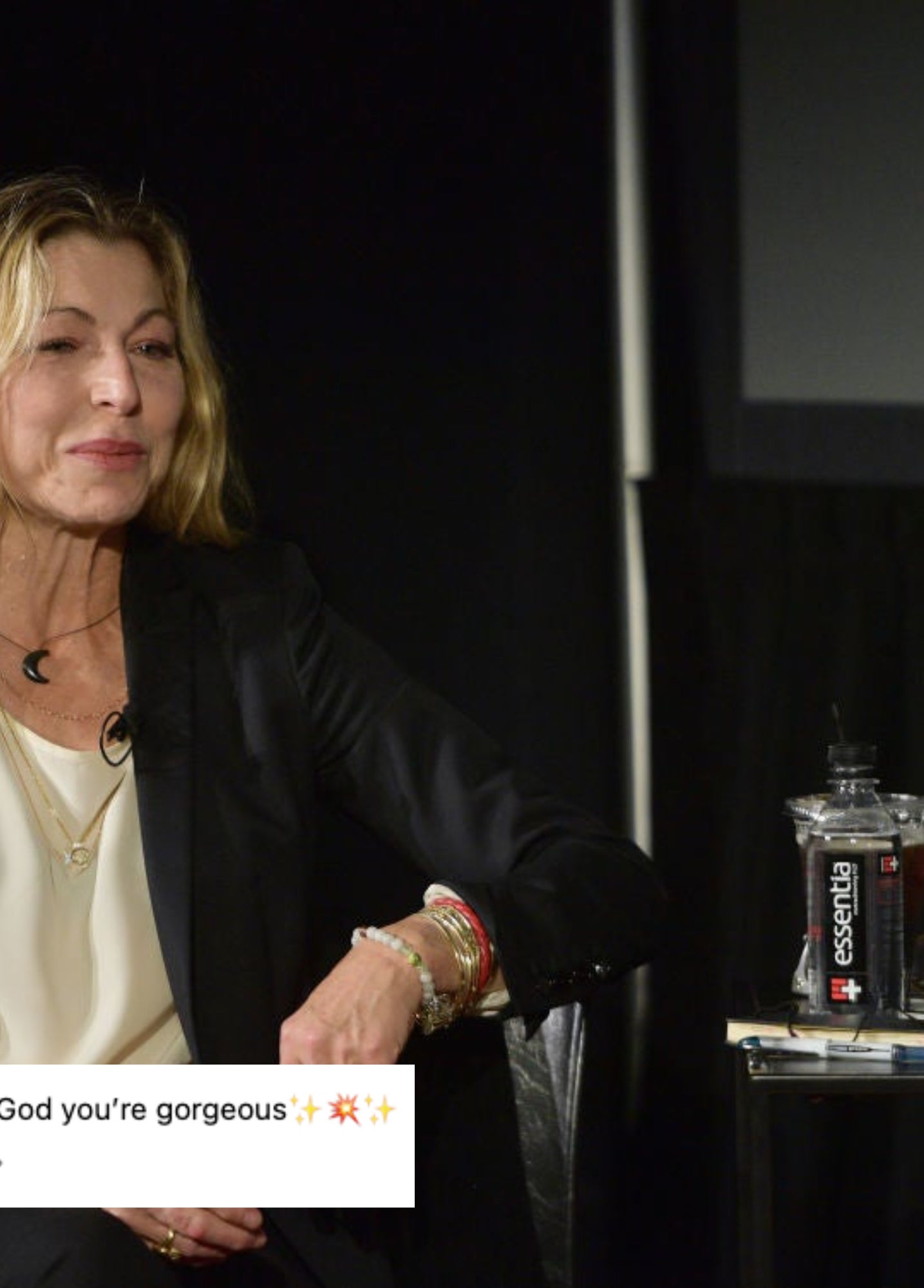 Tatum O'Neal sitting, wearing a blazer and top, with water bottles and microphones on the table during a discussion panel