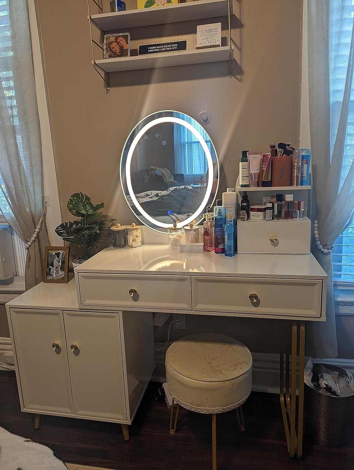 Vanity table with a circular mirror and beauty products, accompanied by a stool