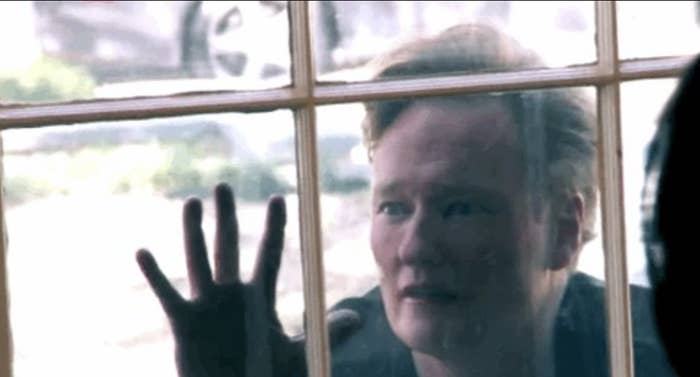 Person pressing hand against a window pane, with a reflective expression