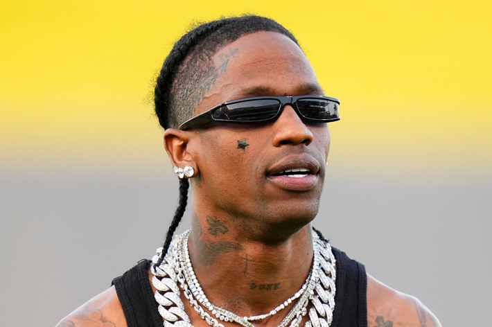 Travis Scott wearing sunglasses, chains, and a sleeveless top